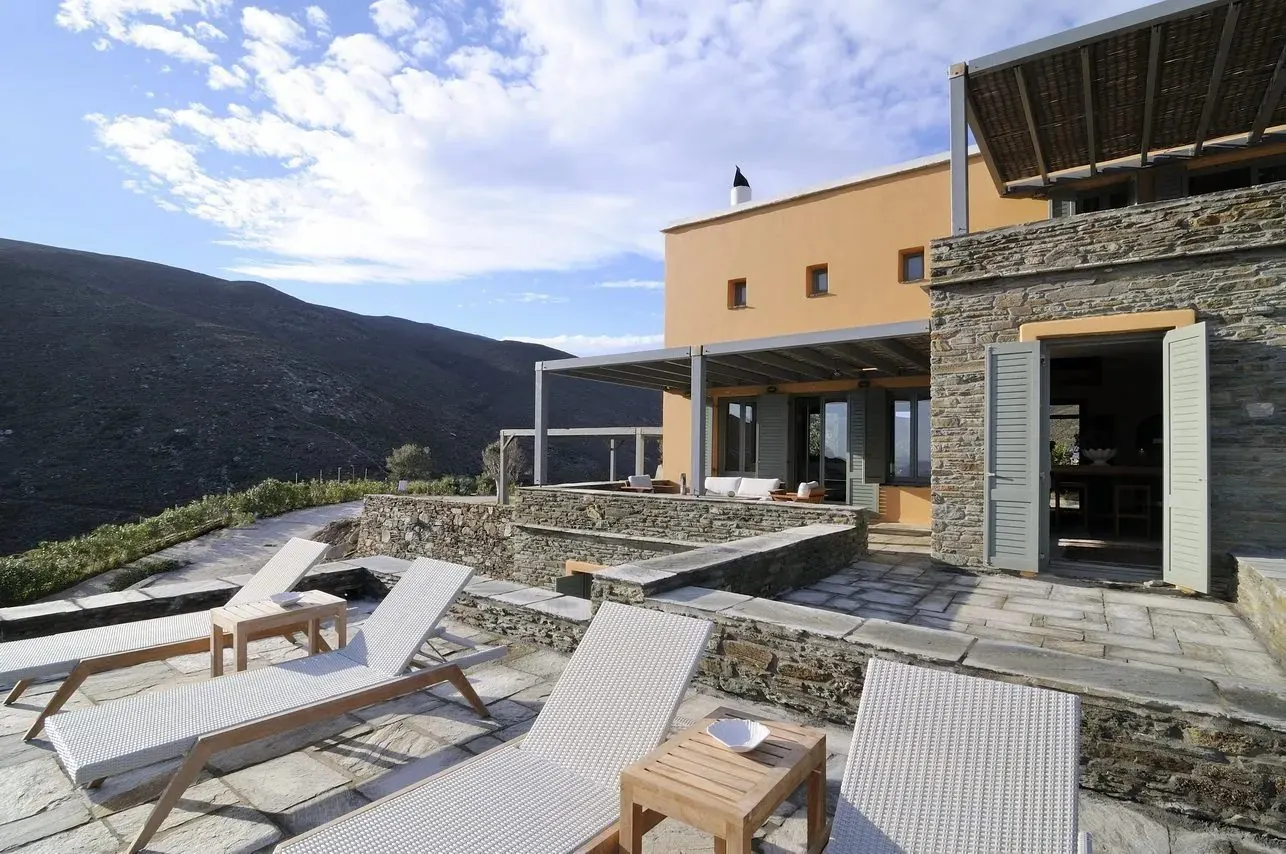 Πέτρινα κτίσματα και ξαπλώστρες στο Aegea Blue Cycladic Resort, Άνδρος